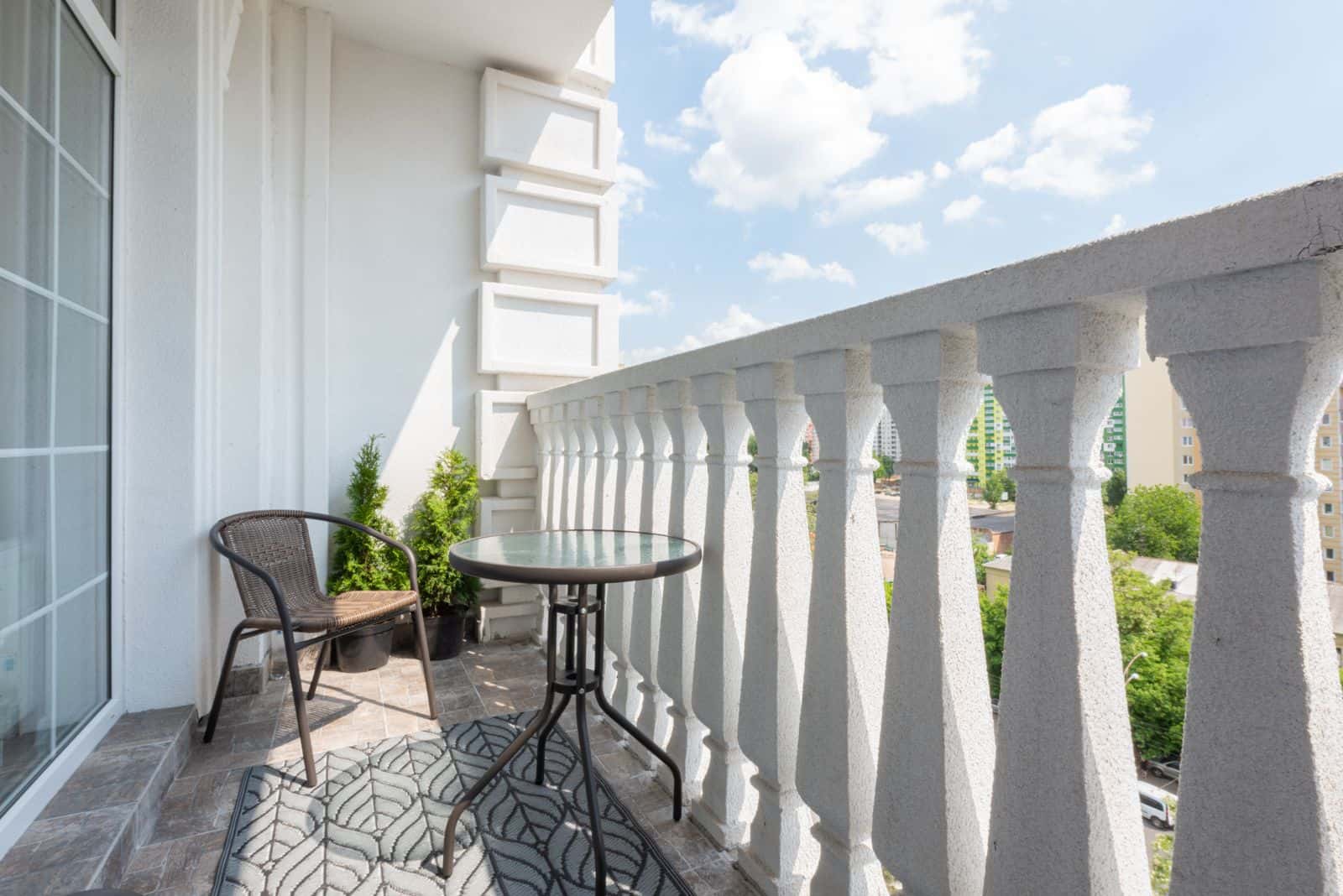 Un balcon ensoleillé avec une petite table, une chaise et une plante verte