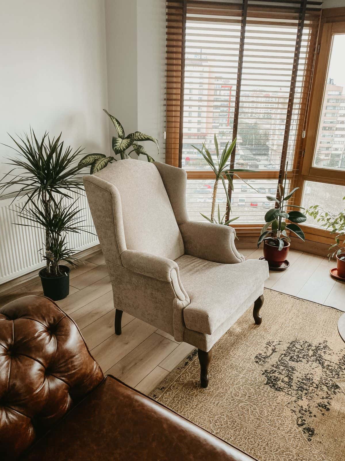 Un fauteuil beige près d'une fenêtre, entouré de plantes vertes