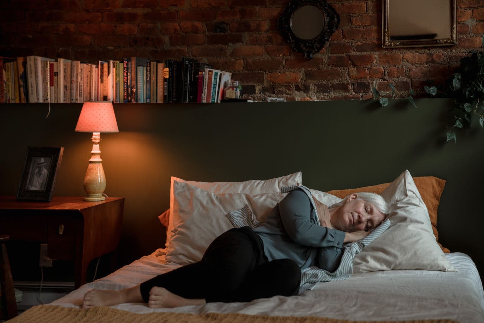 Une femme âgée dort sur le côté dans une chambre éclairée par une lampe de chevet