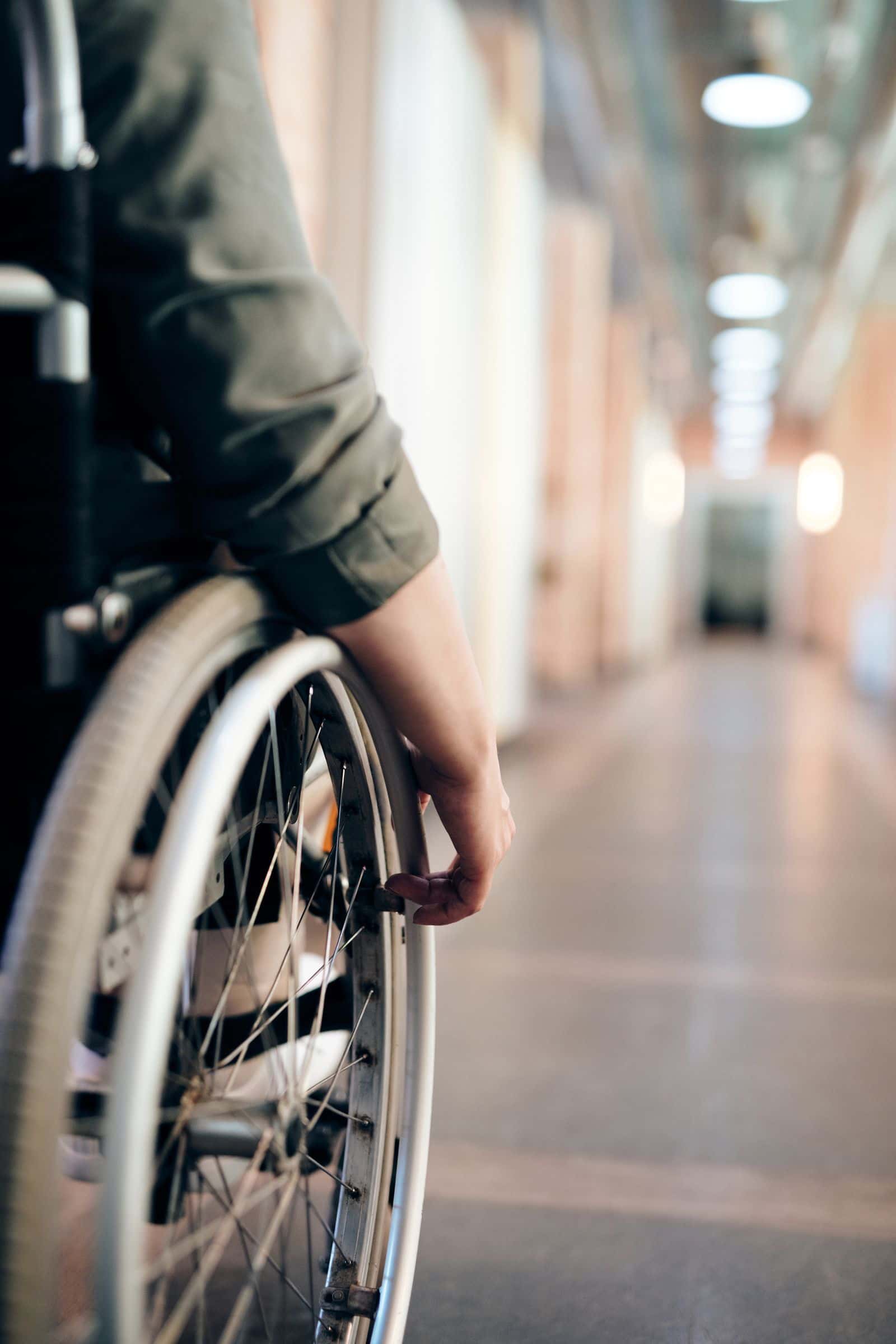 Une main posée sur la roue d'un fauteuil roulant dans un couloir lumineux